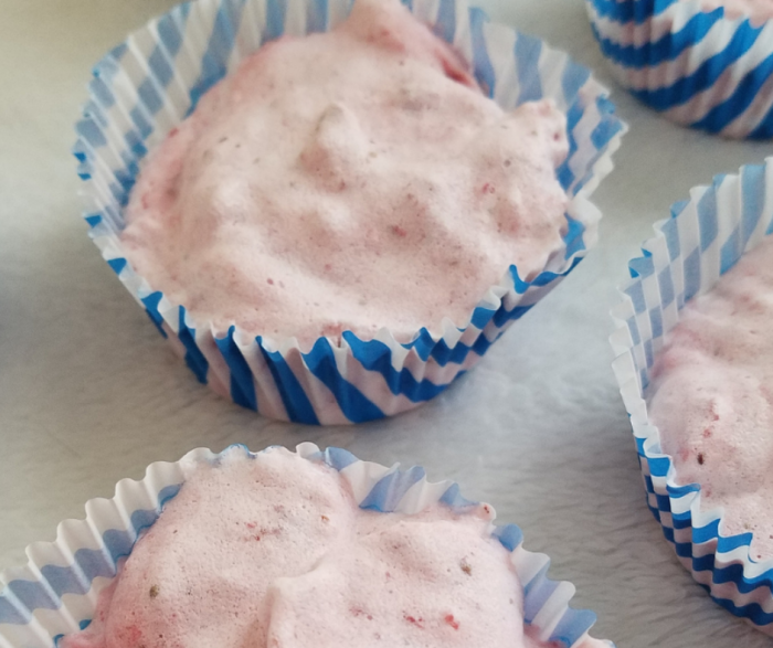 Overhead picture of strawberry fruit ice cream in cupcake liners sitting on a white surface