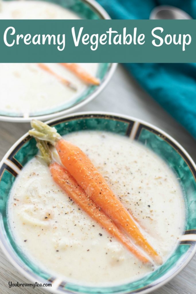 two teal and white bowls filled with creamy vegetable soup and sitting on as light colored surface with teal napkin in the background