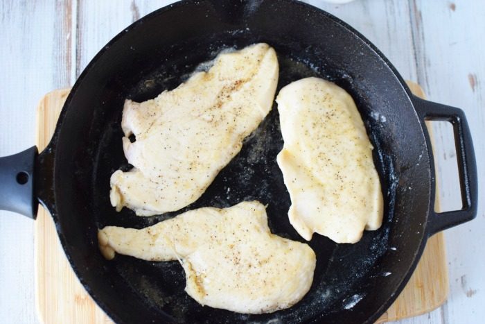 chicken piccata frying in a cast iron skillet