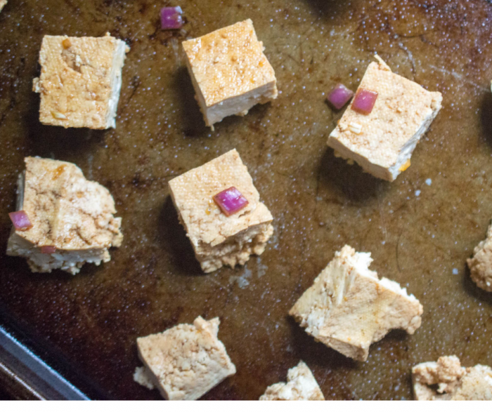 Tofu laying on a baking sheet ready to cook for crispy tofu and broccoli