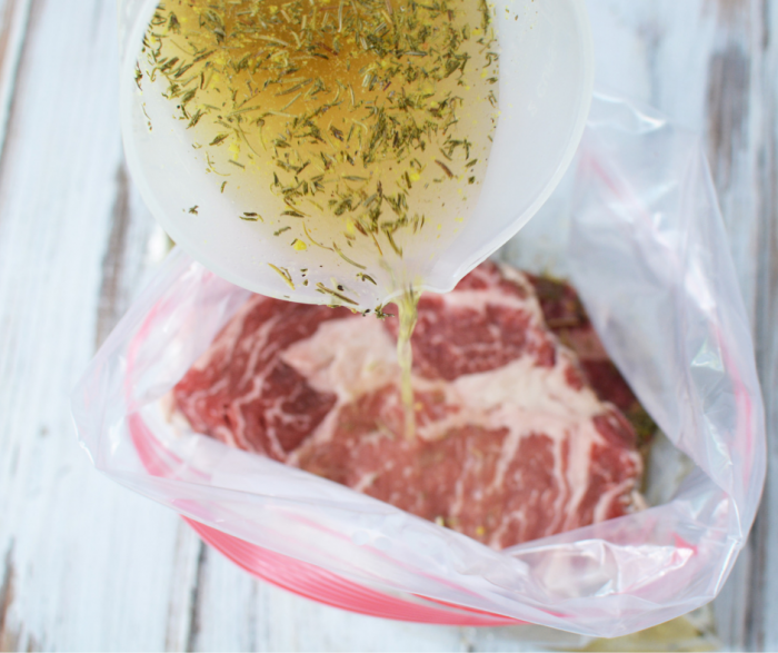 ribeye steak in a ziploc bag with marinade being poured over it