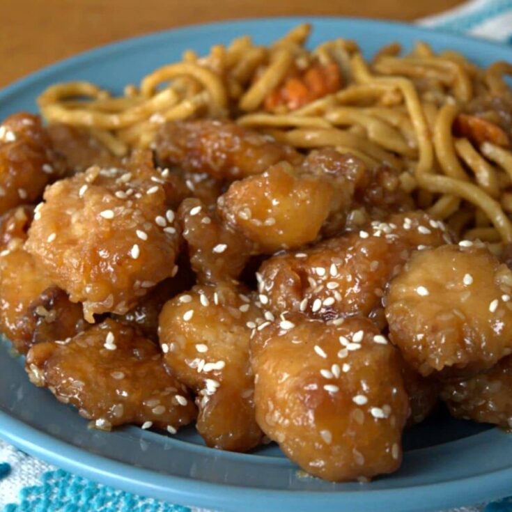 sesame chicken on teal plate with noodles