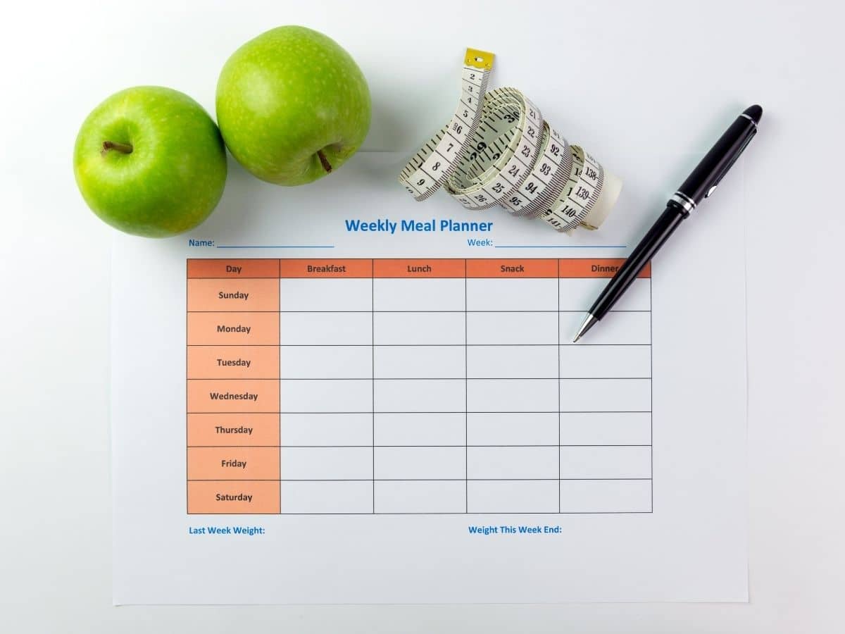 meal planner on white table with tape measure and apples