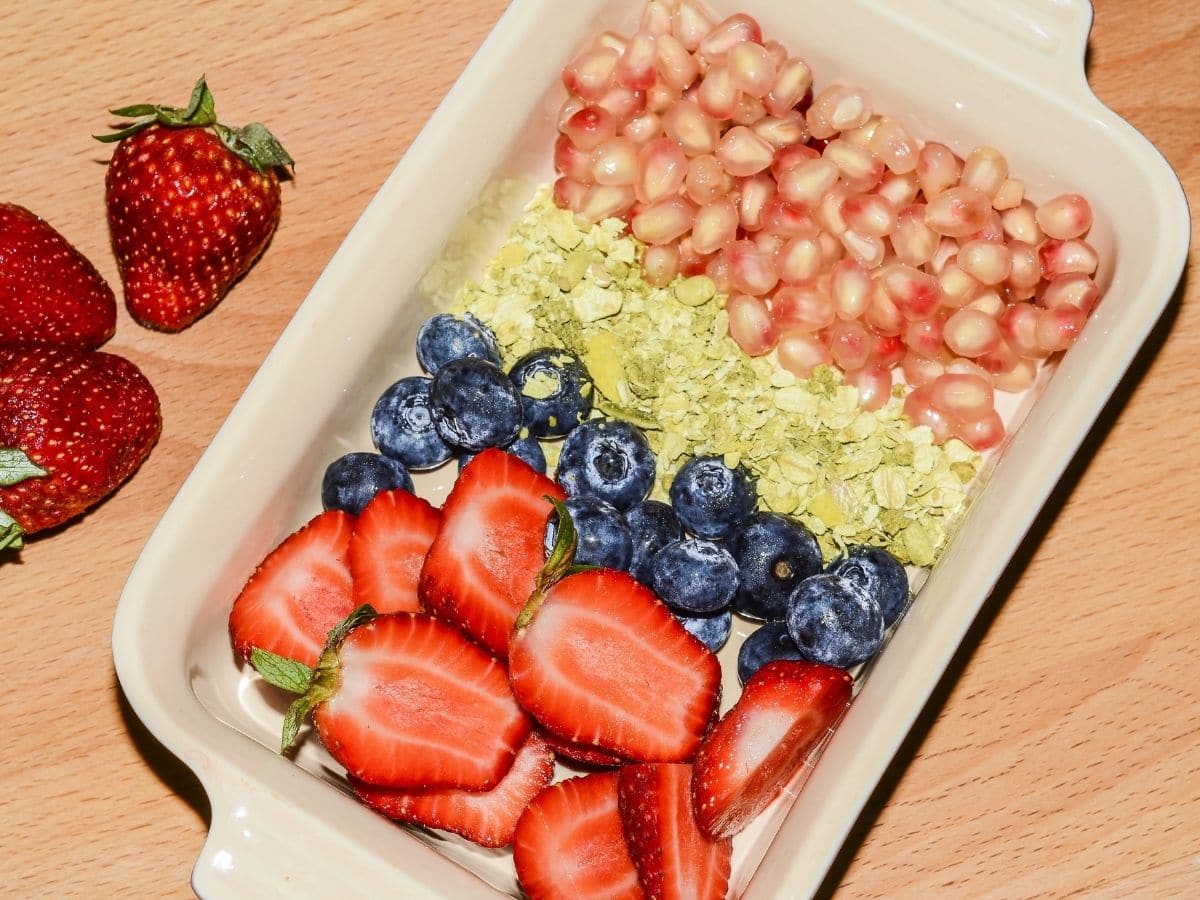 cream platter with strawberries blueberries and seeds on table