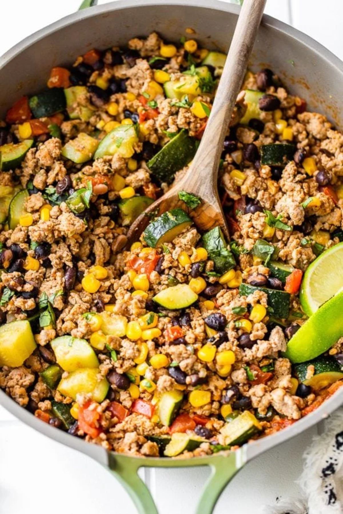 wooden spoon in skillet with ground meat corn and black beans