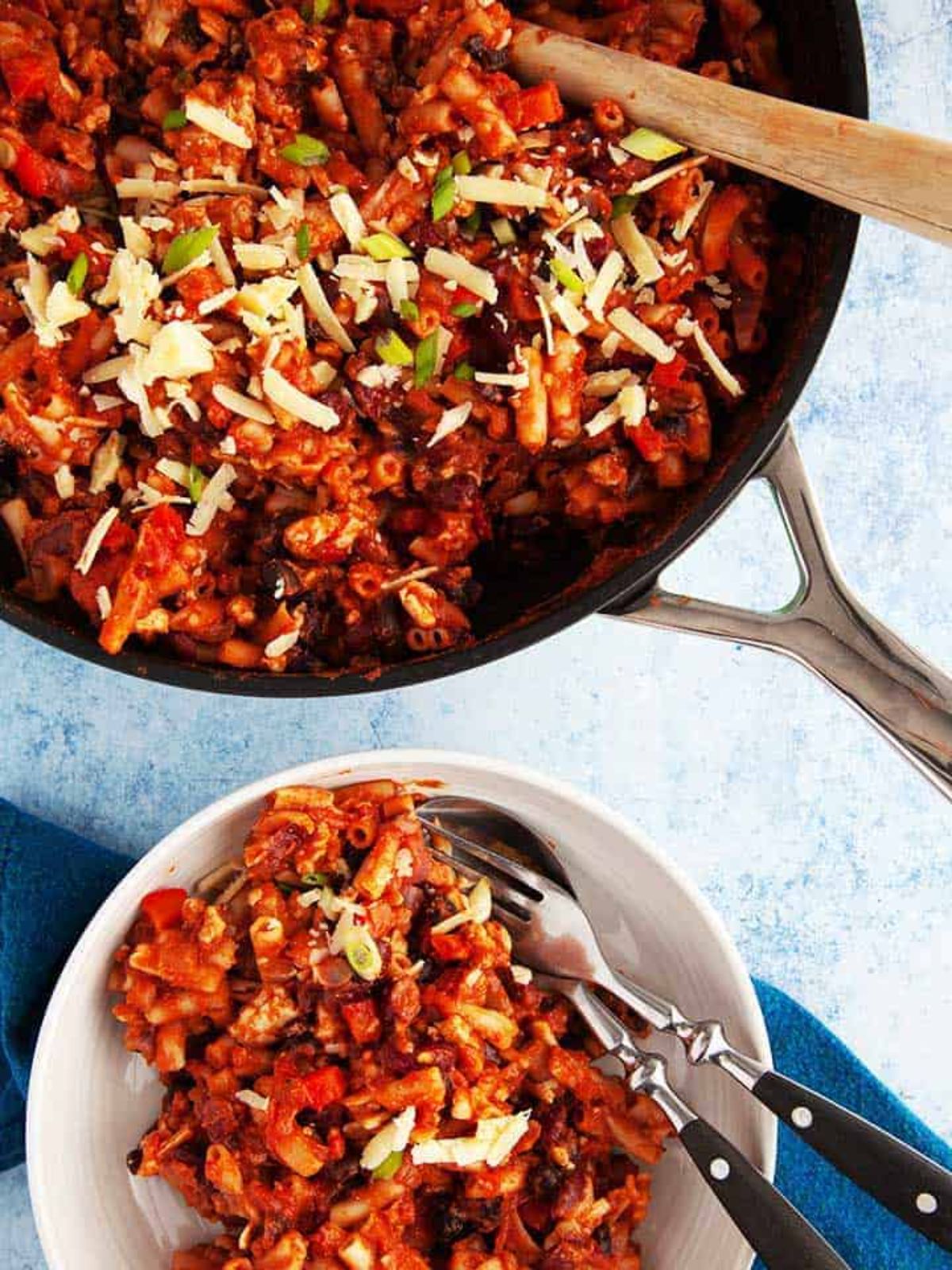 skillet of chili mac next to white bowl of chili mac