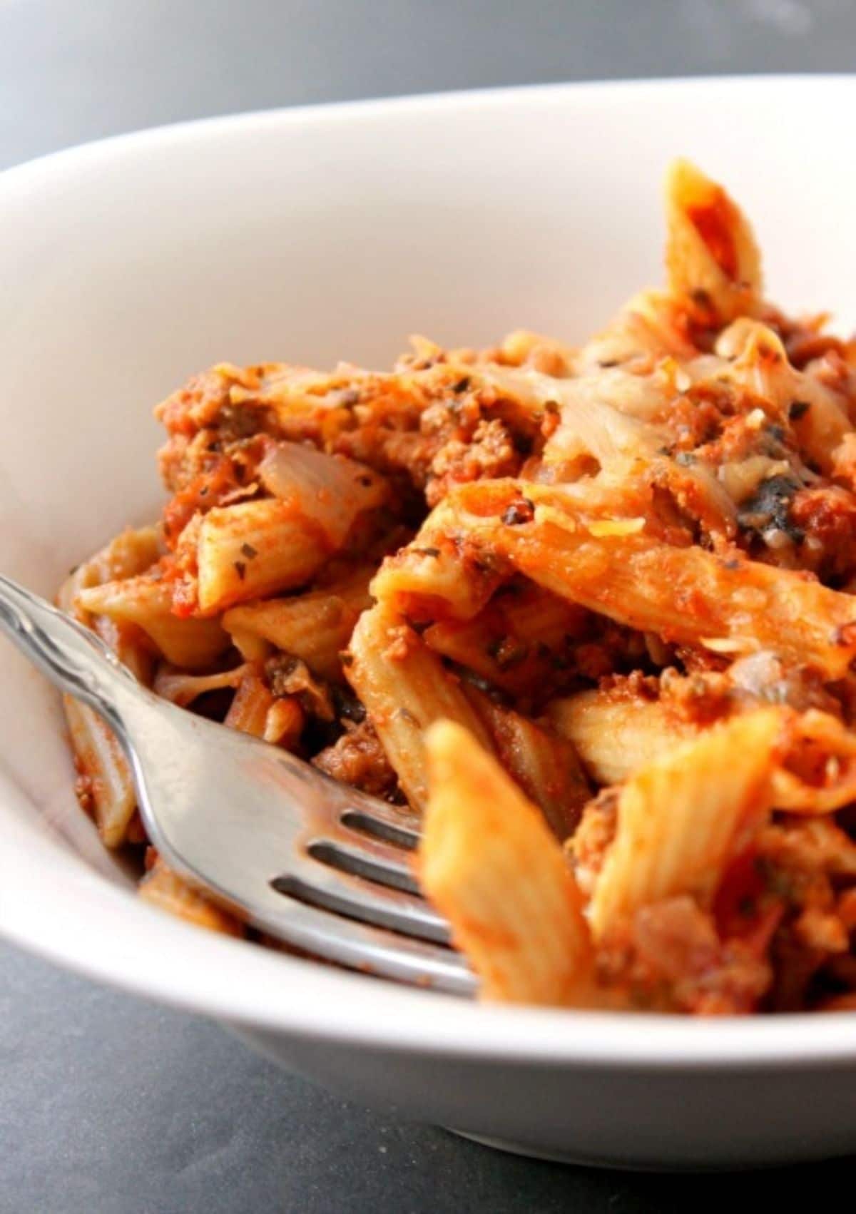 fork in white bowl of pasta