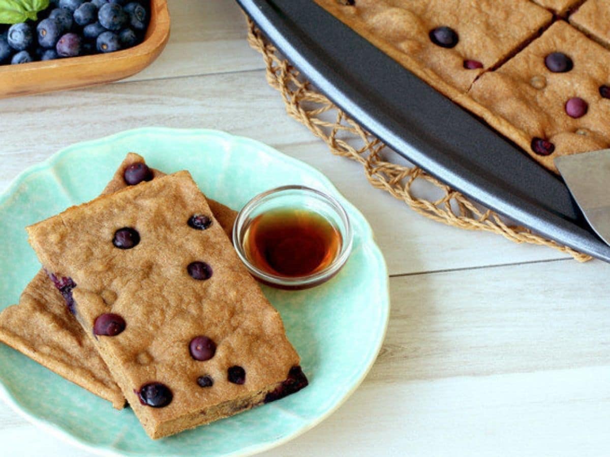 slices of blueberry pancake on teal plate by baking dish