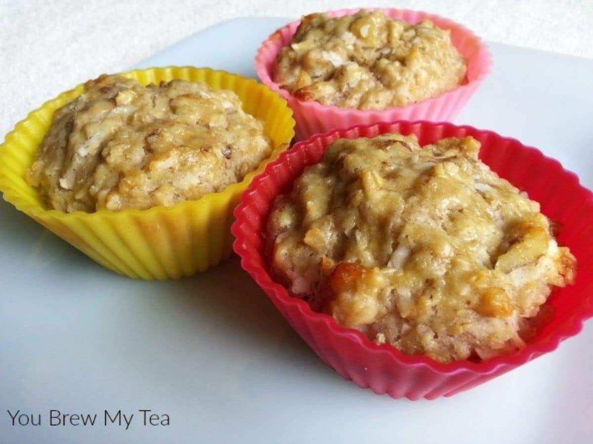 three muffins in pink and yellow silicone muffin cups on white plate