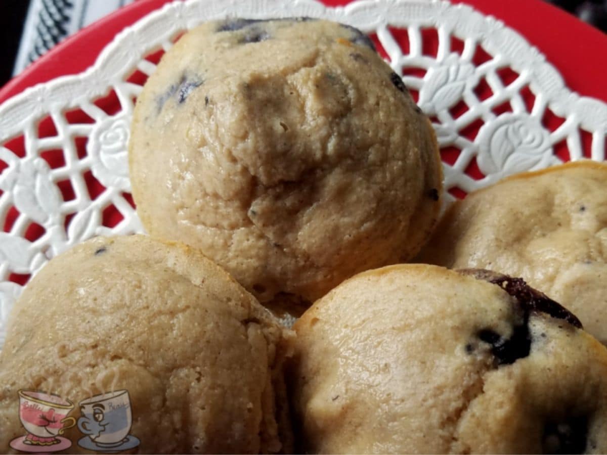 blueberry muffins on white doily on top of red plate