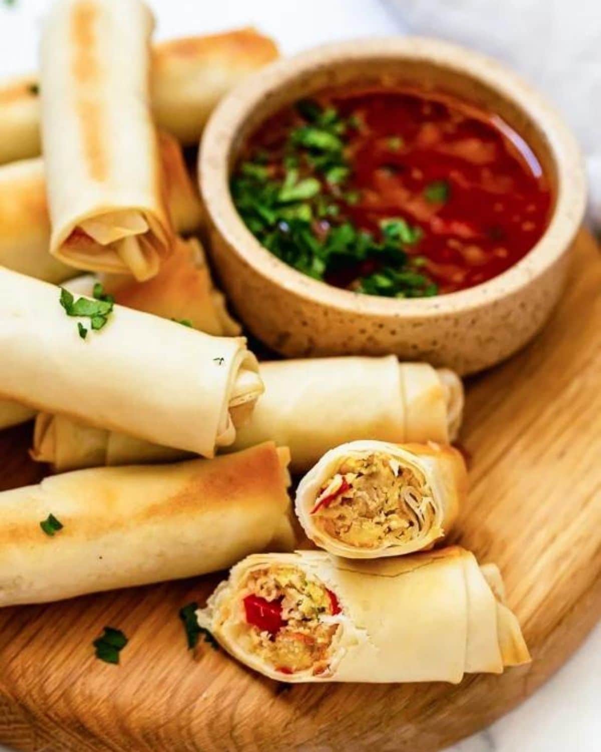 egg rolls on cutting board by dipping sauces