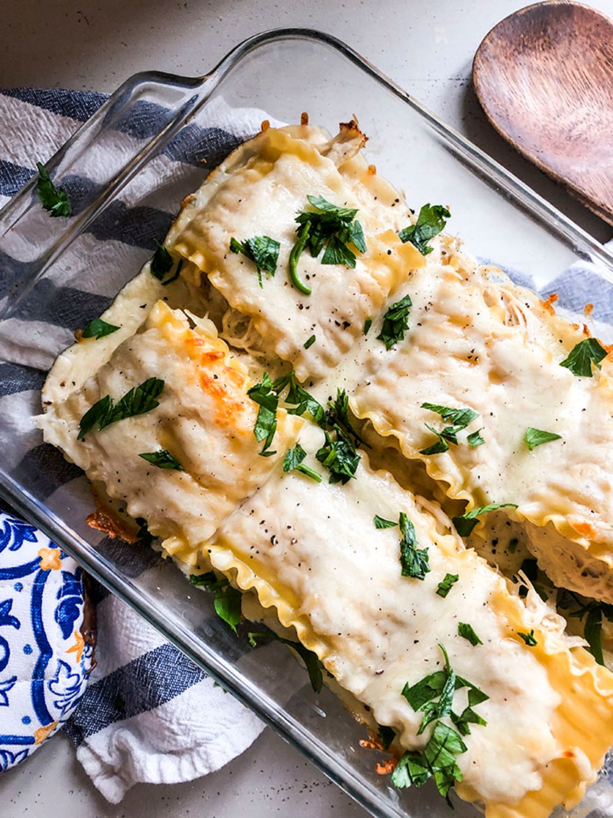 lasagna rolls in glass baking dish on top of striped napkin