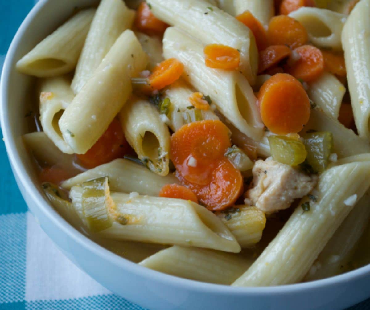 chicken penne soup with carrots on teal checked napkin