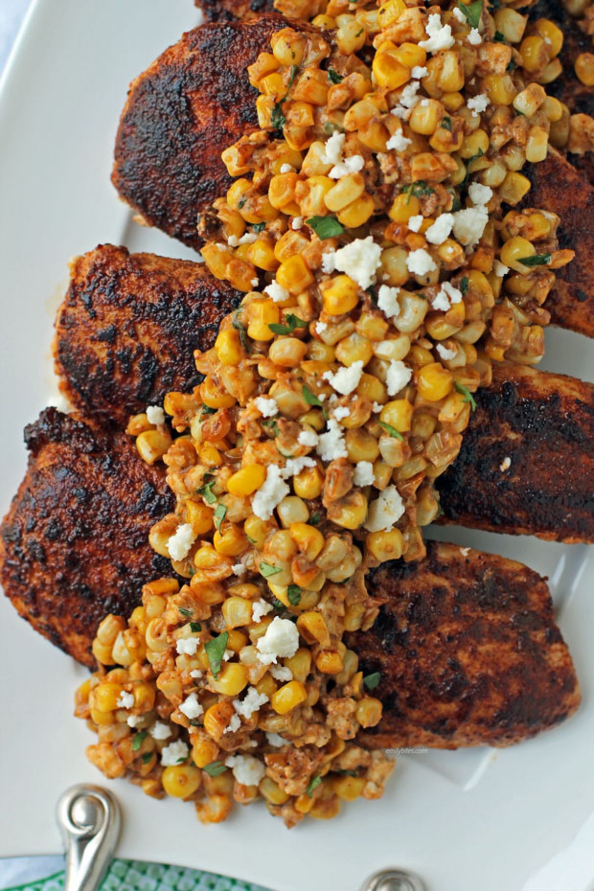 street corn over blackened chicken on white platter