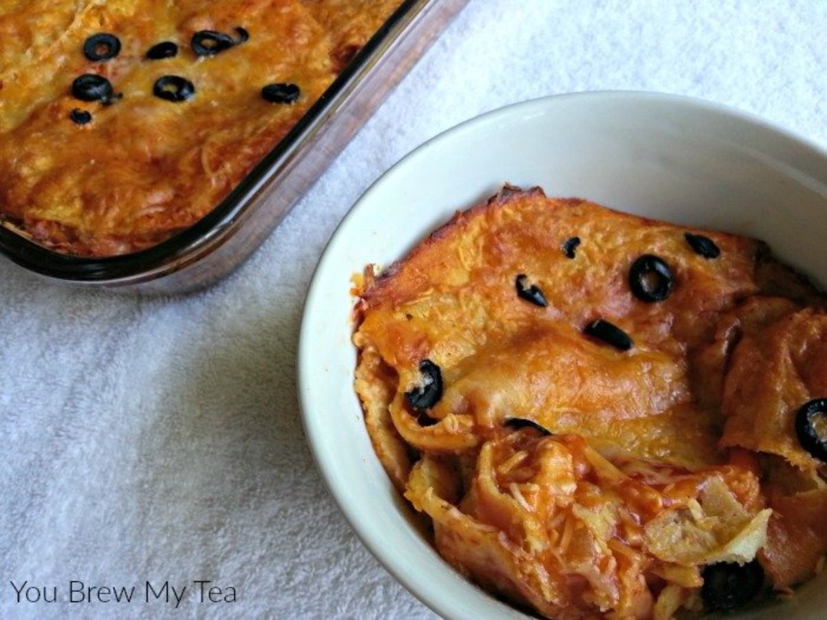 enchilada bake in white bowl on white tablecloth