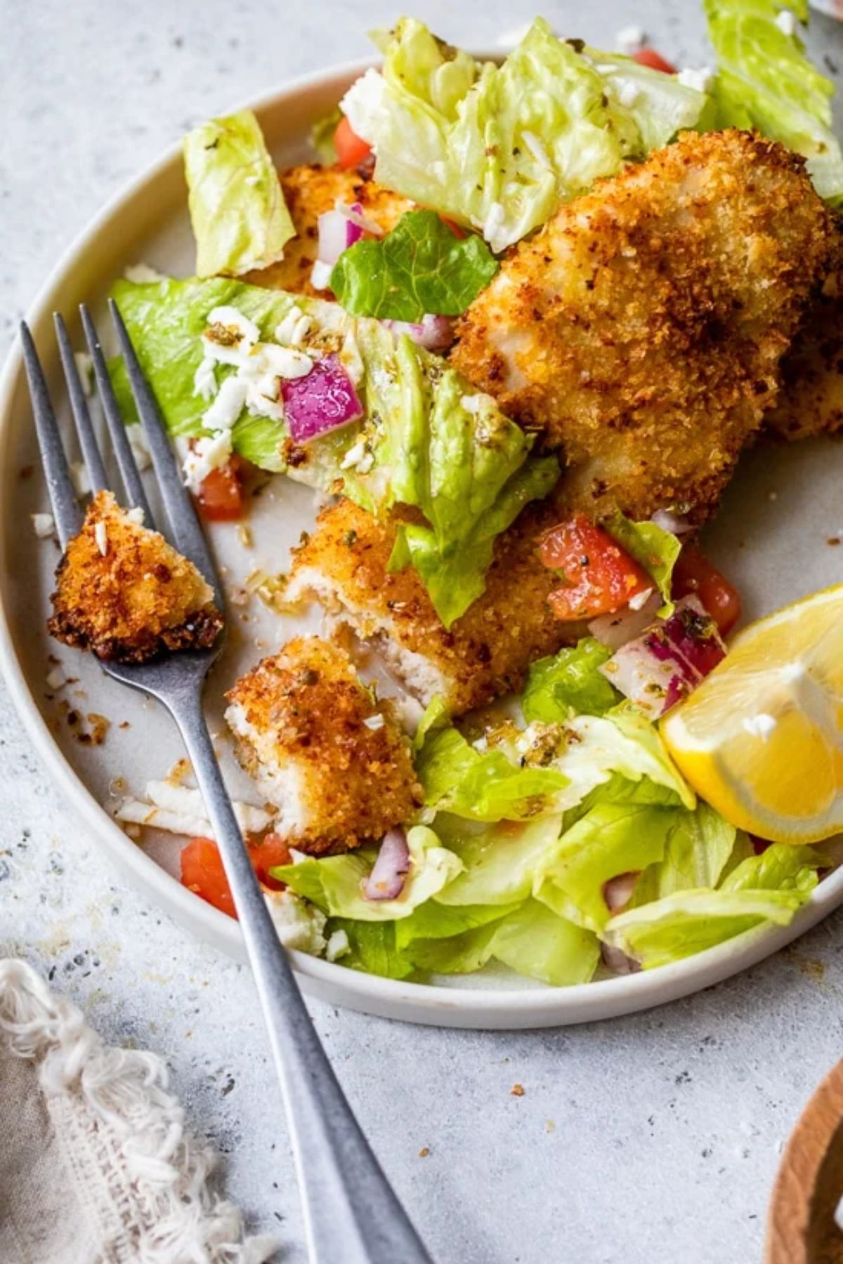 salad on shallow bowl with fried chicken cut into pieces