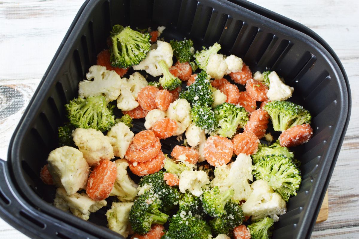 black air fryer basket filled with roasted vegetables